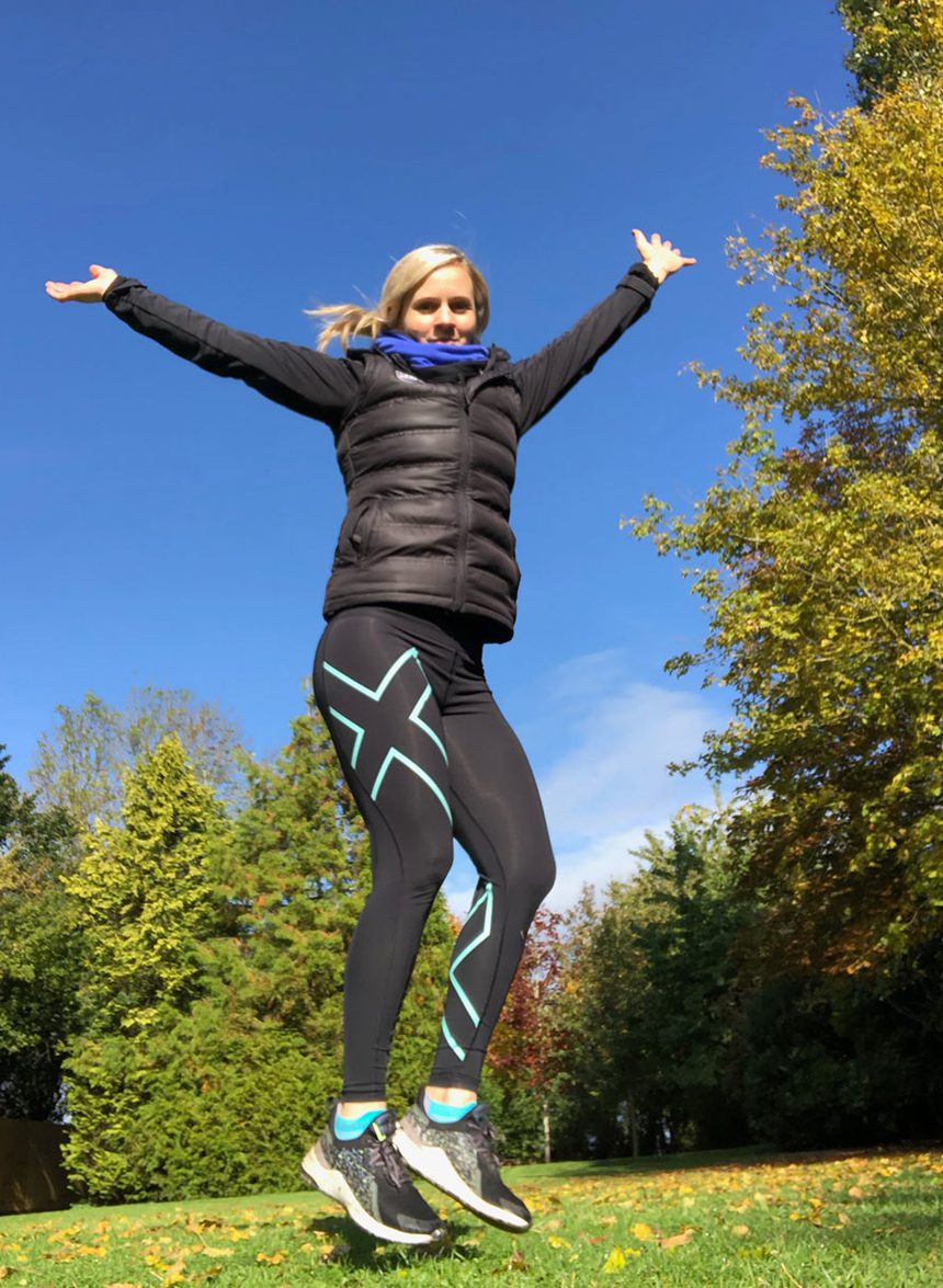 Ann-Louise jumping for joy on the lawn on a sunny day
