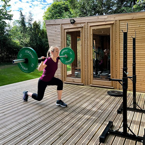 Lunging with a barbell on the decking outside the garden studio